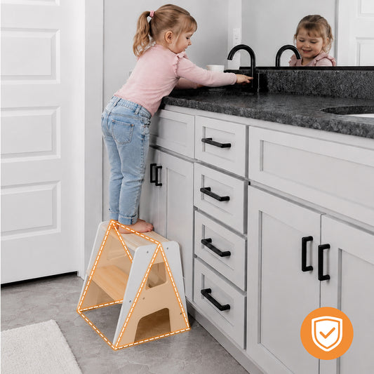 Toddler standing on a wooden step stool helping in the kitchen