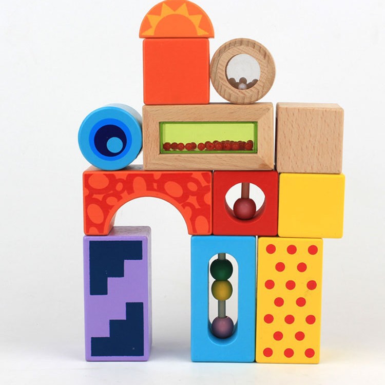 Kind spielt mit Sound Blocks aus Holz, bunten Klötzen, die beim Bewegen Geräusche erzeugen und die Sinnesentwicklung fördern.