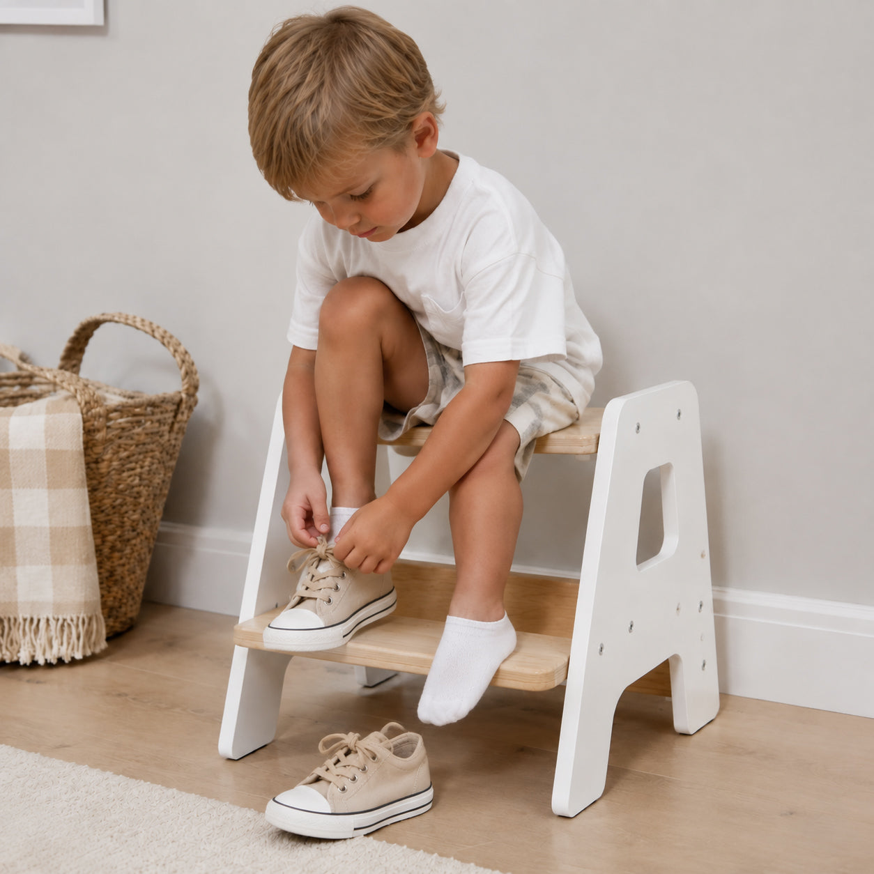 Child sitting on a Montessori step stool while putting on shoes