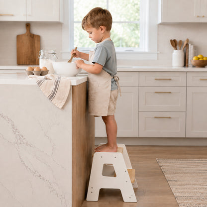 Toddler using a wooden kitchen step stool to participate in cooking activities