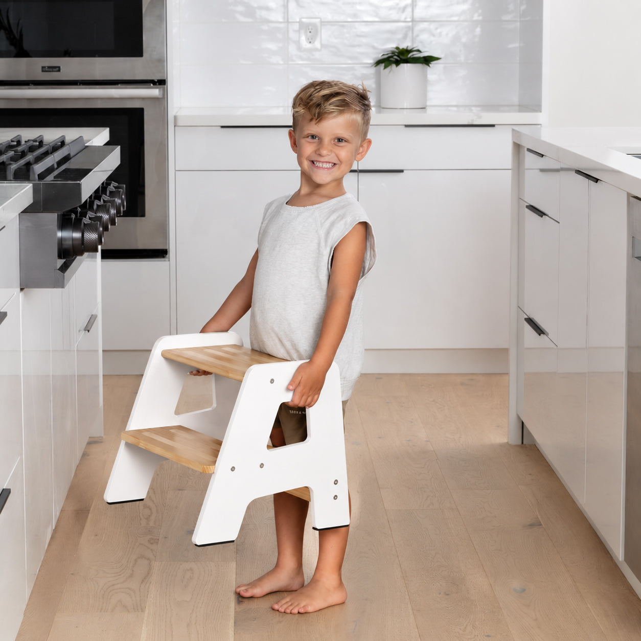 Child carrying a lightweight Montessori step stool with easy grip design