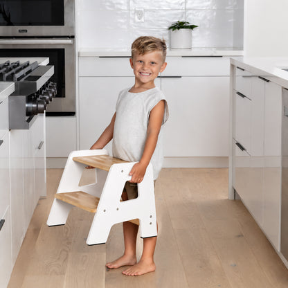 Child carrying a lightweight Montessori step stool with easy grip design
