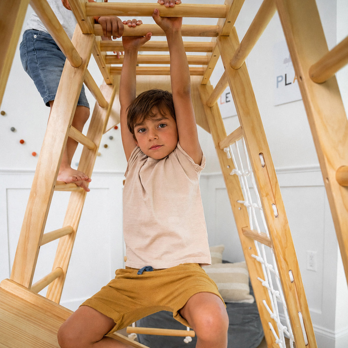 Kind beim Hangeln an den oberen Sprossen des Indoor-Klettergerüsts
